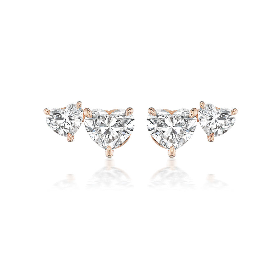 The Duo Studs in Rose Gold with Heart Diamonds feature two clear gemstones on each earring, set in minimalist 18K rose gold for an elegant look.