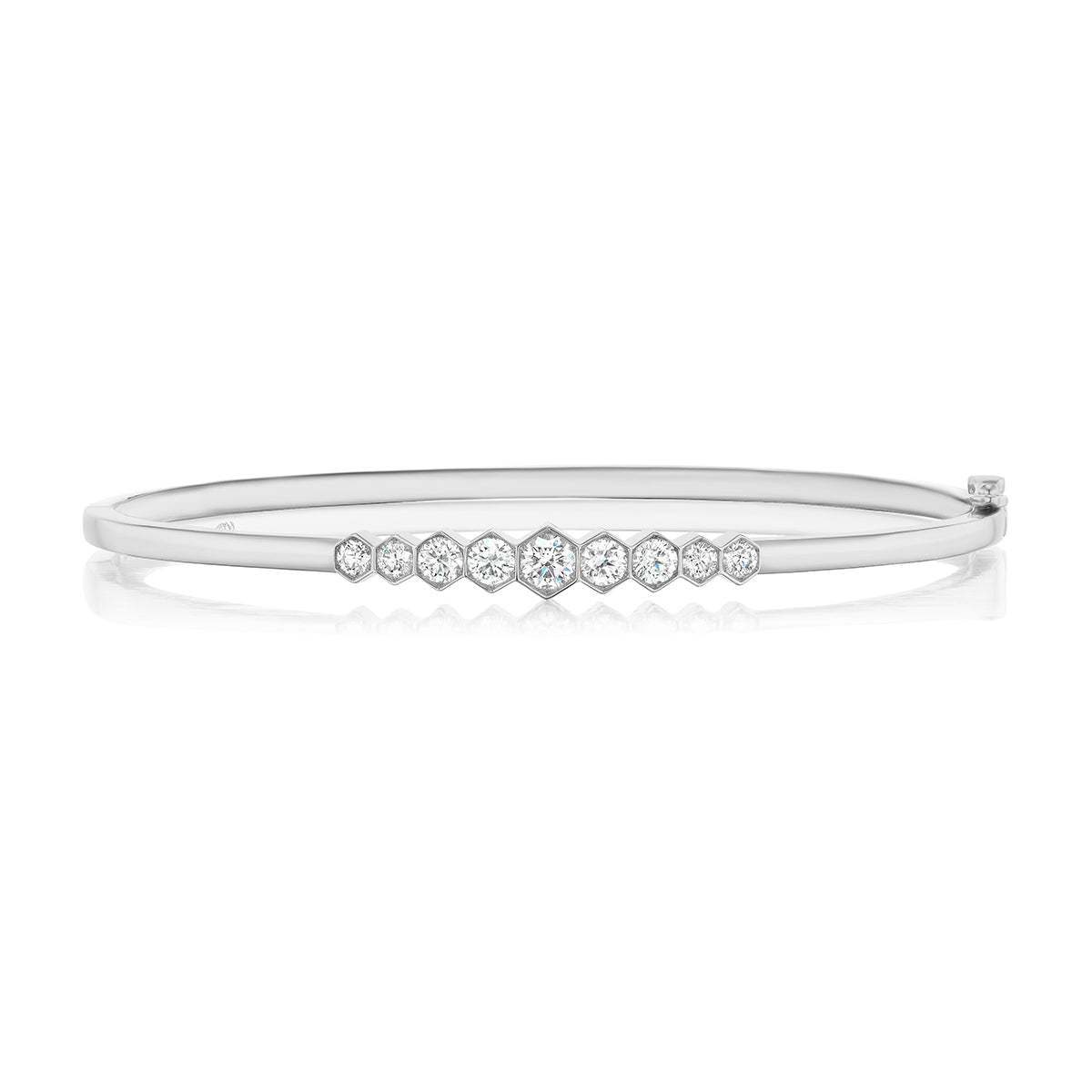The Graduated Hexagon Bezel Set Diamond Bangle showcases a sleek silver design with round and hexagonal diamonds bezel set in the center, arranged in a graceful graduated pattern.