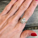 A hand with red nail polish wears two rings on the ring finger: a gold band and a diamond ring paired with the Marquise and Round Diamond Ring Jacket in Yellow Gold, which features an oval center stone and a fan of marquise diamonds.