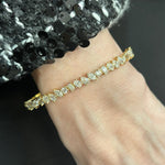 A close-up of a wrist wearing the Marching Mixed Shape Diamond Bangle in 18K rose gold, set with sparkling stones, paired with a black and white sequined sleeve.