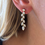 Close-up of a woman's ear wearing Marquise Diamond Waterfall Drop Earrings, featuring a gold leaf-inspired design with marquise and brilliant cut diamonds arranged in a cascading pattern.