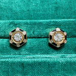 The Hexagon Alternating Onyx and Diamond Ear Jackets feature 18K yellow gold, a central round diamond, black onyx accents, and delicate diamond details, shown against a textured green fabric background.