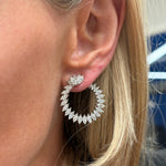 Close-up of a woman wearing Cluster Marquise Climbing Ivy Front to Back Hoops—large, circular earrings encrusted with marquise-cut diamonds that shine against her straight, blonde hair.