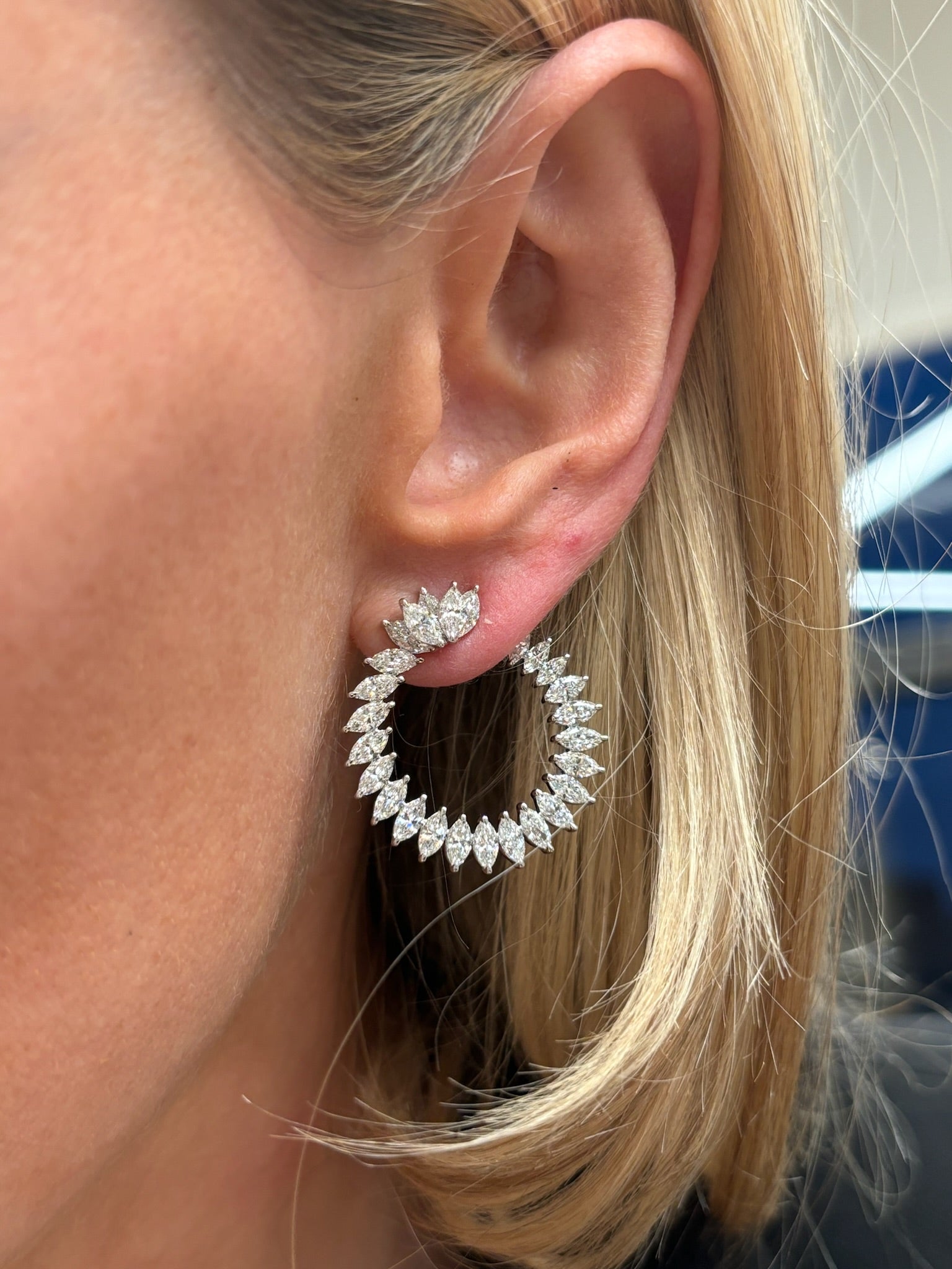Close-up of a woman wearing Cluster Marquise Climbing Ivy Front to Back Hoops—large, circular earrings encrusted with marquise-cut diamonds that shine against her straight, blonde hair.