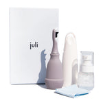 The Juli Diamond Cleaning Essentials Kit includes an electric toothbrush, white storage case, tonic bottle, light blue cloth, and a Juli-branded box—ideal for use with your diamond cleanser or favorite jewelry cleaning system.