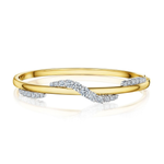 The Coil Wave Diamond Bangle in Yellow Gold and Platinum showcases a stunning wavy design, beautifully accentuated with rows of sparkling natural diamonds set along the elegant curve and at both ends.