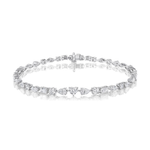 The East-West Mixed Shape Tennis Bracelet is a delicate silver piece showcasing alternating round and emerald-cut clear gemstones, presented on a white background with a shiny reflection below.