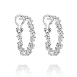 The Mixed Shape Diamond Hoops feature silver hoops adorned with alternating round and baguette-cut clear gemstones, displayed on a white background with a subtle reflection beneath each earring.