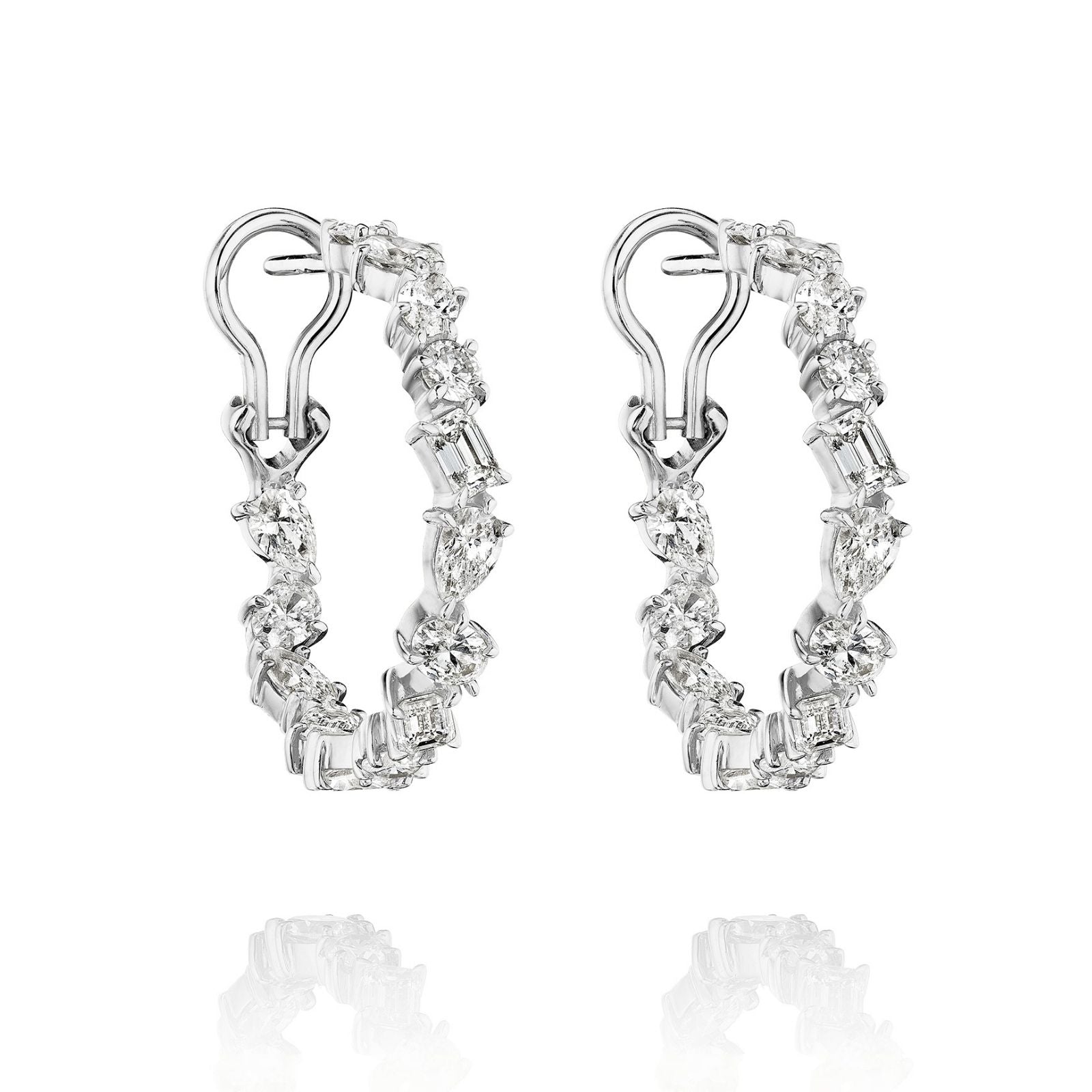The Mixed Shape Diamond Hoops feature silver hoops adorned with alternating round and baguette-cut clear gemstones, displayed on a white background with a subtle reflection beneath each earring.