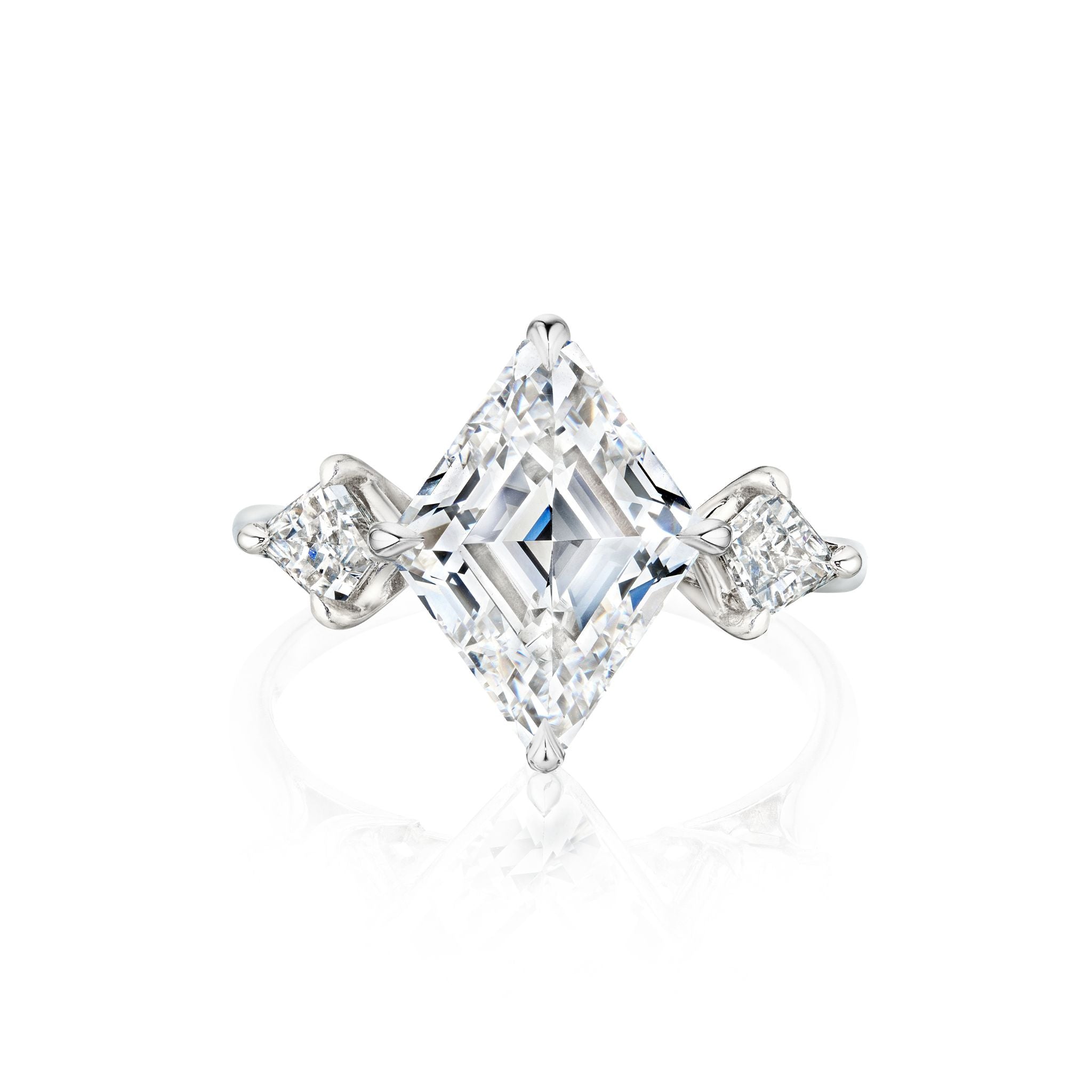The Lozenge Diamond Engagement Ring with Kite Shape Side Stones features a bold center diamond and two kite-shaped side stones set on a slim platinum band, shown against a white background.