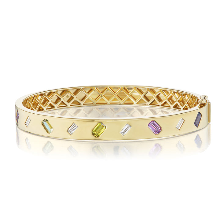 The Mixed Shape Diamond and Multicolor Sapphire Bangle showcases a geometric cutout design, set with rectangular multicolored sapphires, clear stones, and emerald-cut diamonds along the outer surface.