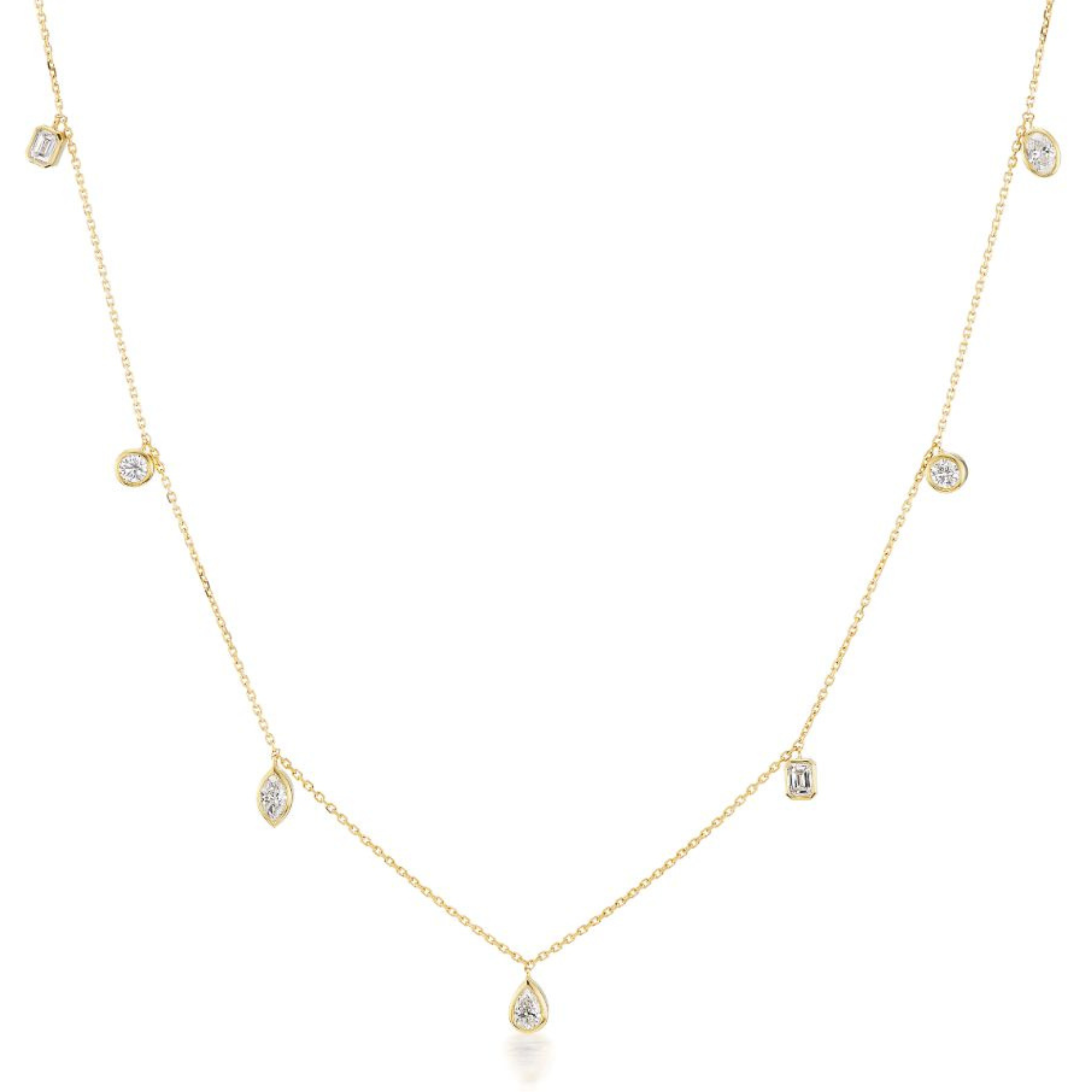 The Mixed Shape Diamond Station Necklace showcases seven bezel-set diamond charms in round, oval, marquise, and pear shapes on a delicate 18K yellow gold chain, beautifully displayed on a white background.