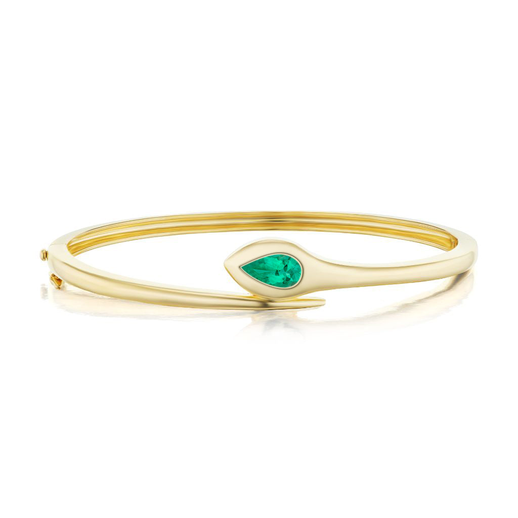The Snake Bangle with Pear Shape Emerald in Yellow Gold is a modern, slightly asymmetric 18K yellow gold bracelet featuring a centrally set pear-shaped emerald.