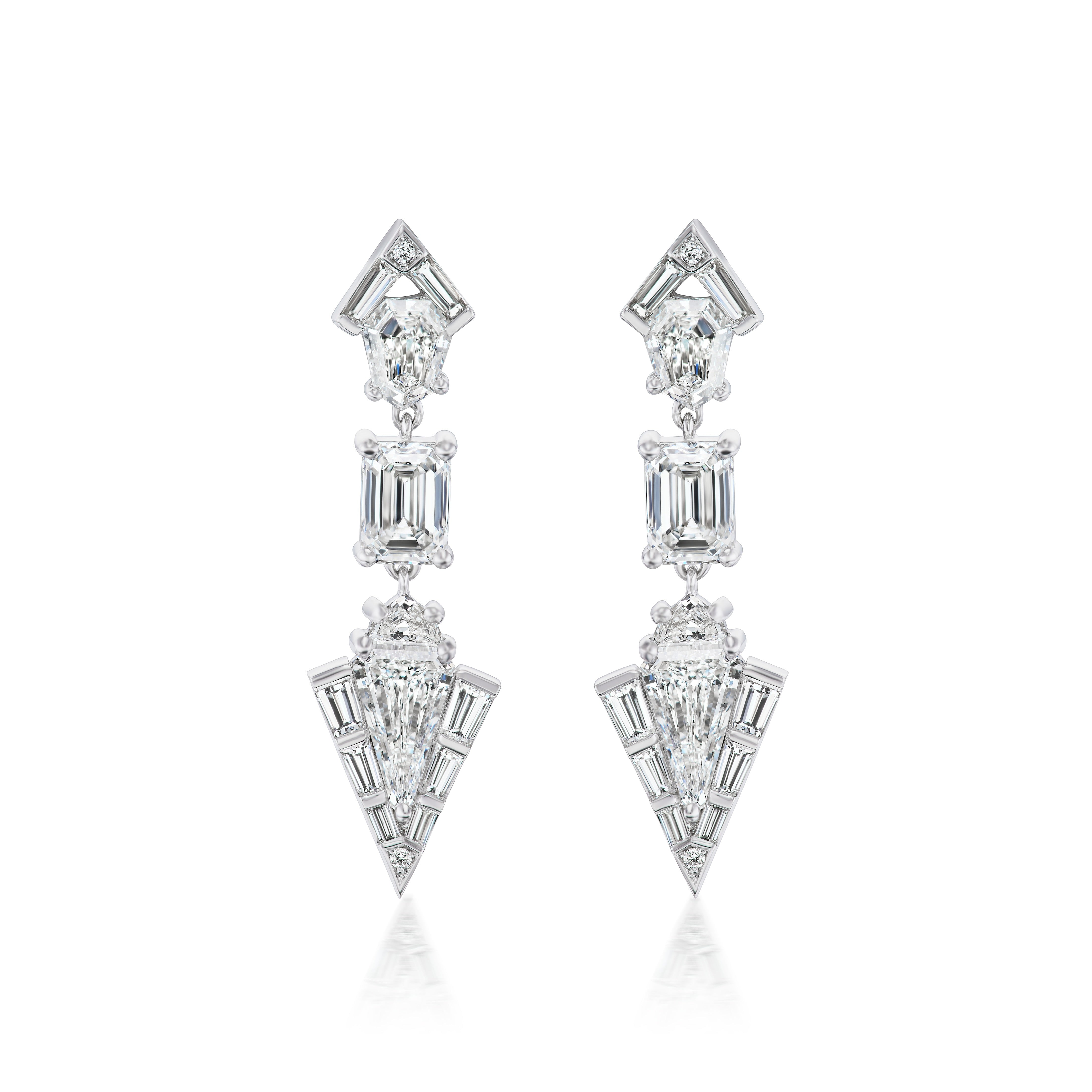Statement Emerald, Baguette, and Round Cut Diamond Drop Earrings in White Gold featuring geometric shapes with baguette and round cut diamonds in triangular, square, and kite-like patterns on a white background.