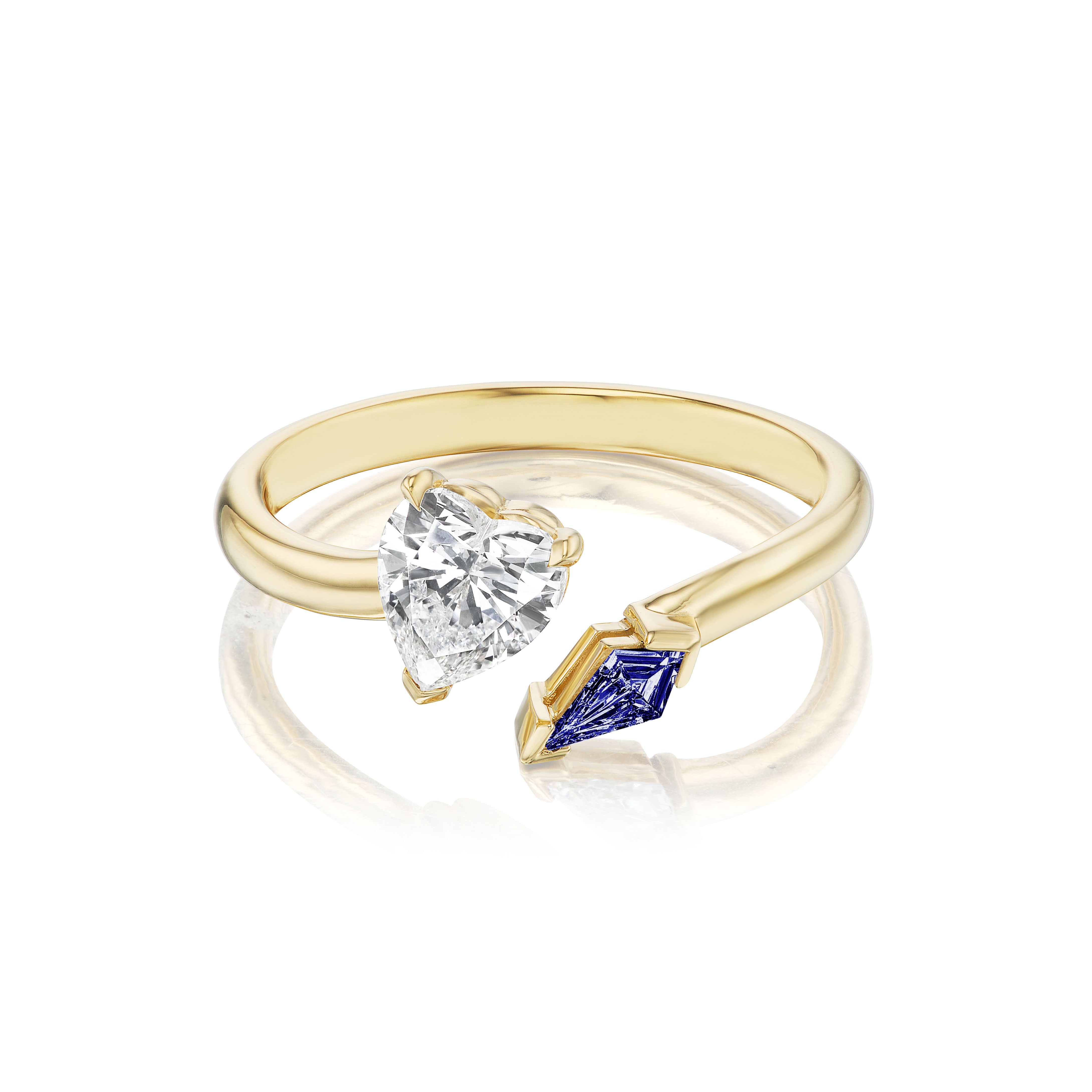 The Toi et Moi Ring features a heart-shaped diamond and a kite-shaped sapphire set in an 18K yellow gold open band design.