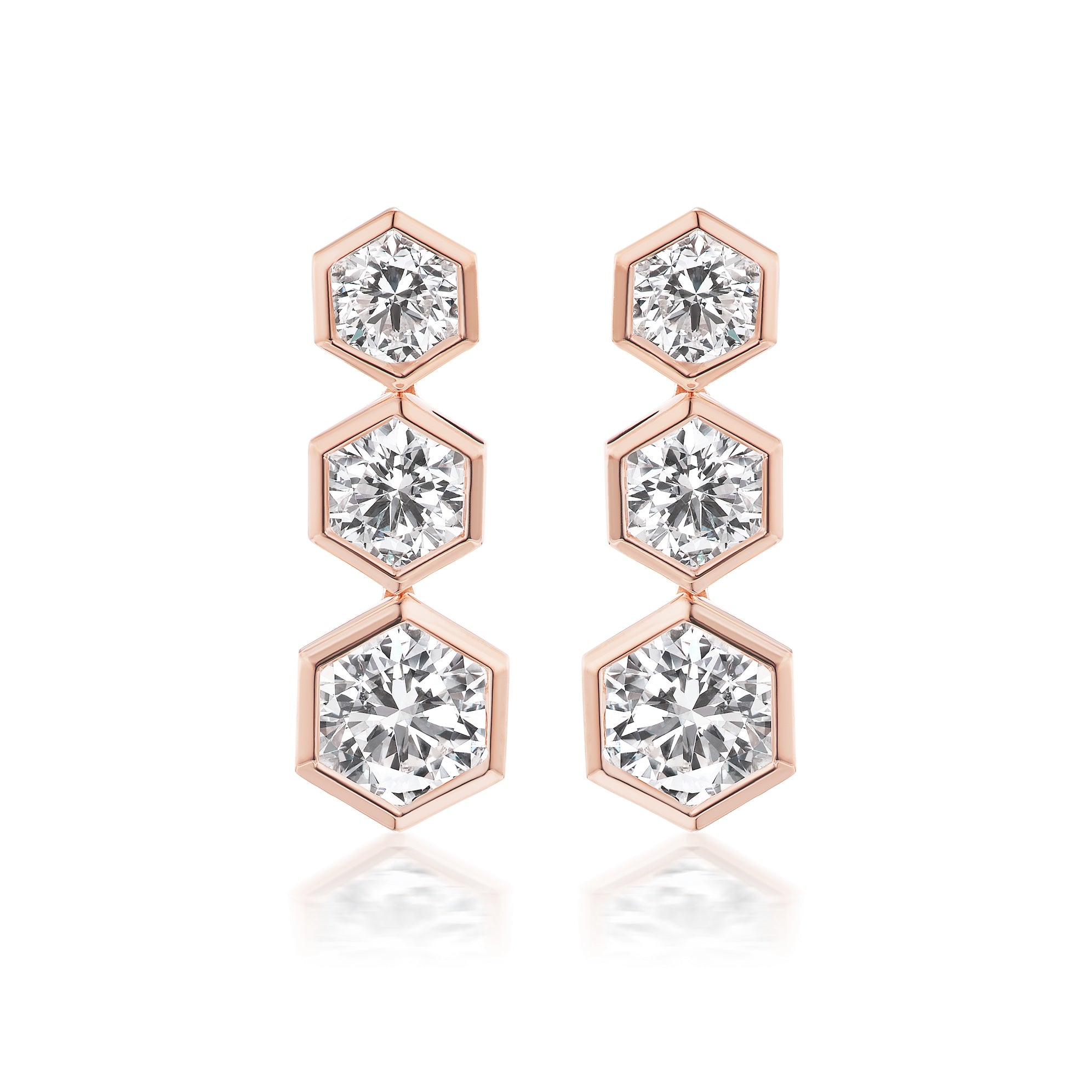 The Graduated Hexagon Bezel Set Drop Earrings feature three round brilliant diamonds in hexagonal bezel settings, arranged vertically by size and crafted in radiant 18K yellow gold.