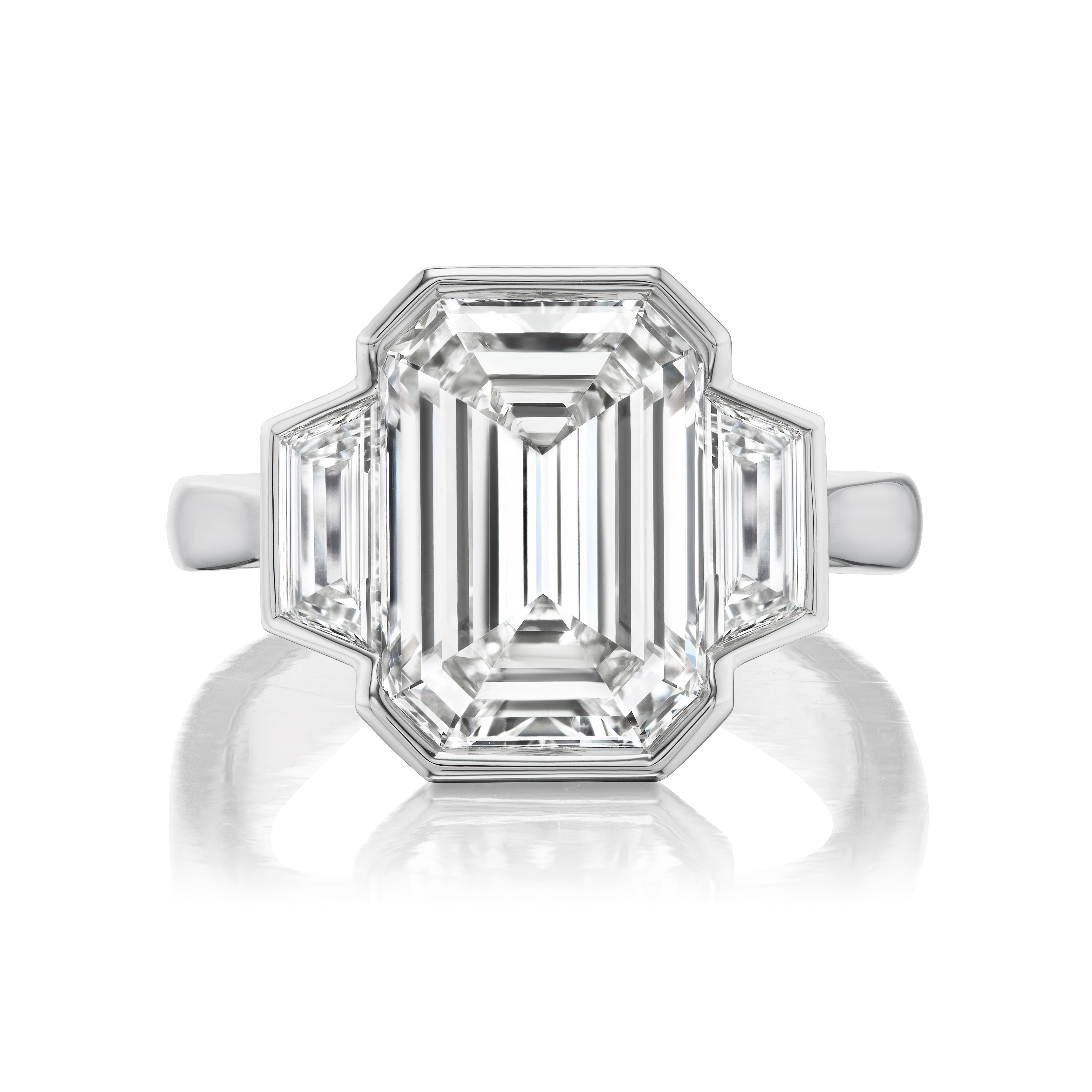 A white gold Emerald Cut Diamond Engagement Ring with a bezel setting, featuring a large center stone and trapezoid side stones for added brilliance.