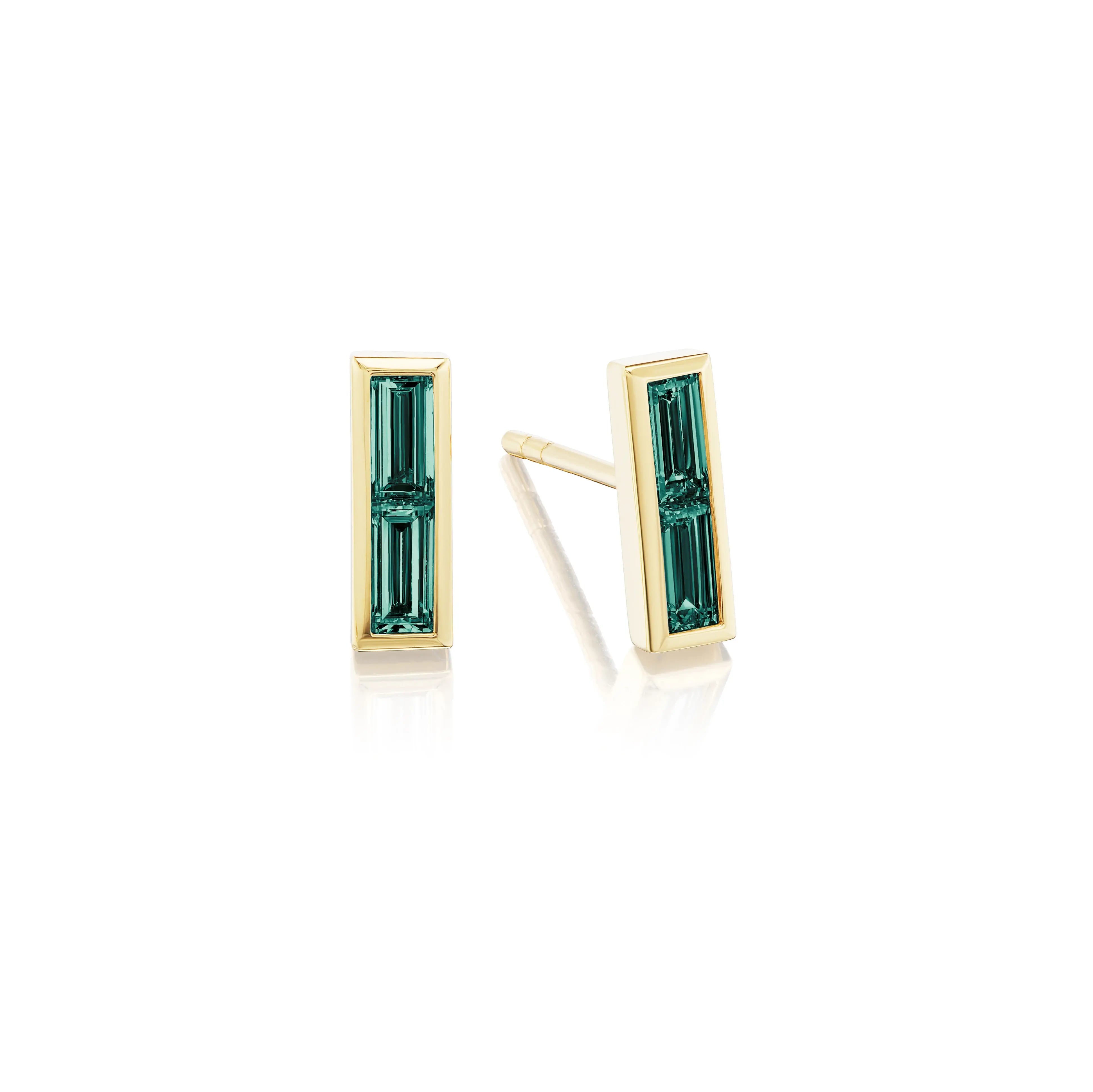 The Bezel Set Baguette Emerald Studs in Yellow Gold feature vertical baguette-cut emeralds in a sleek 18K yellow gold setting, shown on a white background.