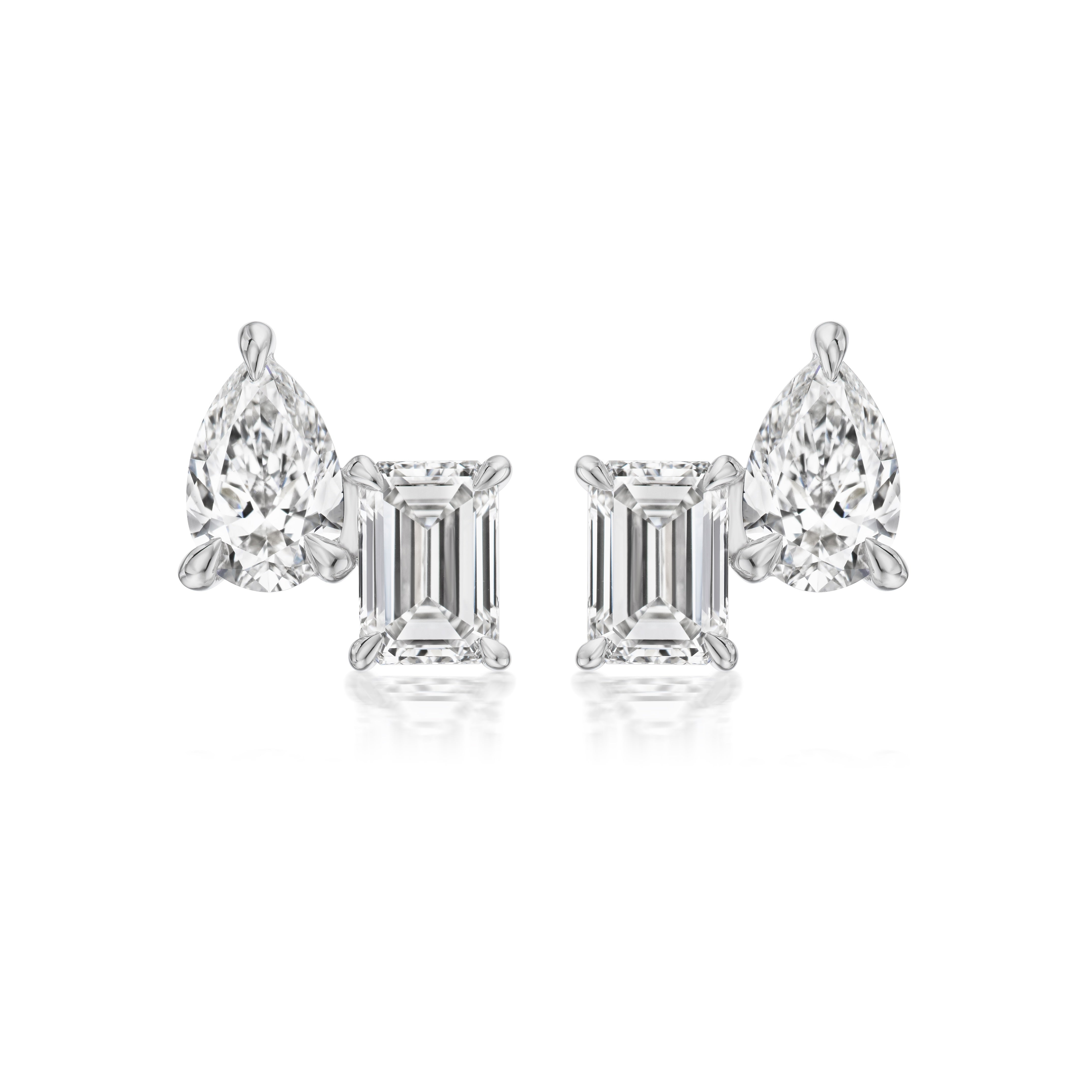 The Mixed Shape Duo Studs feature one emerald cut and one pear shape diamond on each earring, set in 18k white gold, and are displayed on a white background.