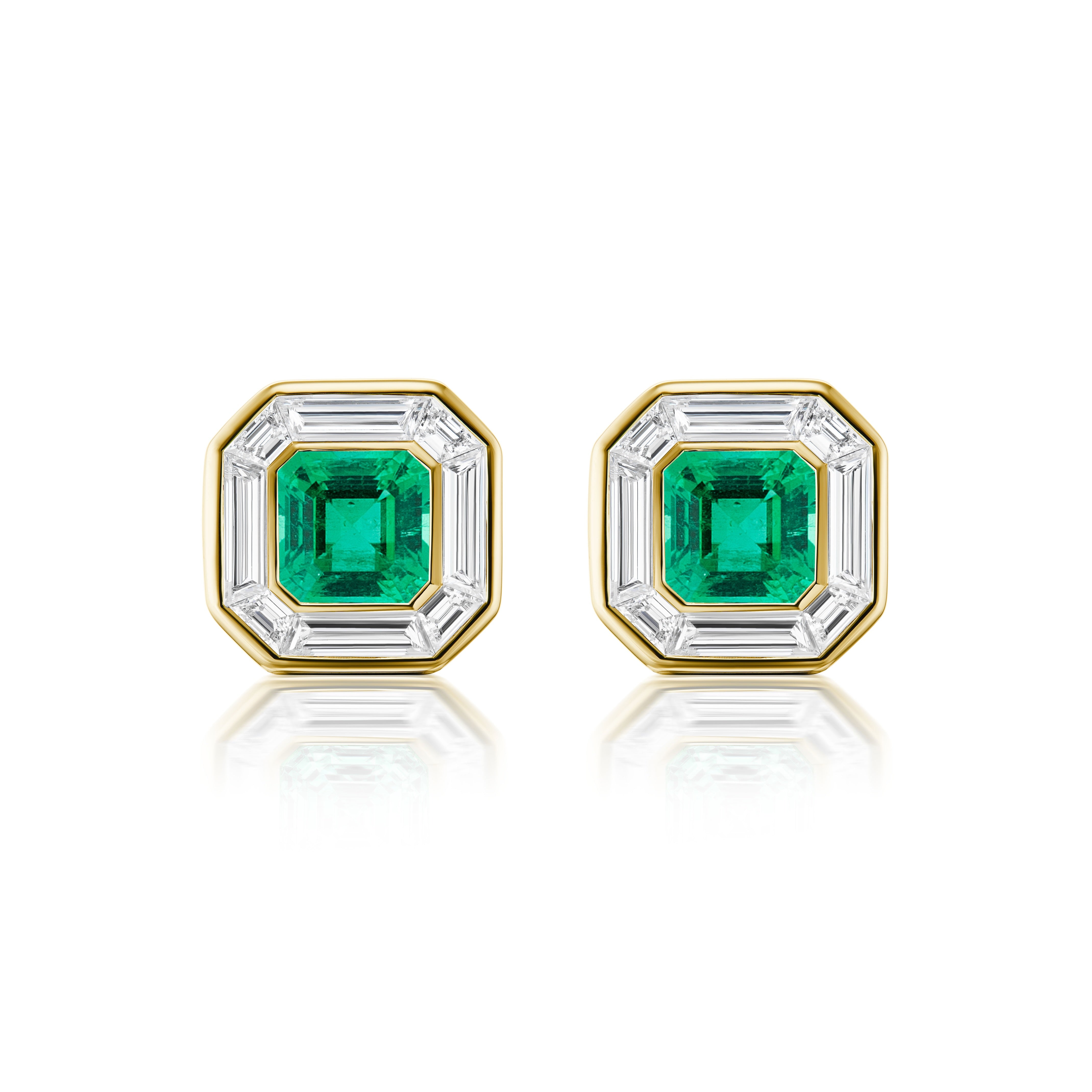 The Mosaic Studs in Yellow Gold showcase Asscher Cut Emeralds at the center, framed by sparkling baguette diamonds and set in 18K yellow gold, displayed on a white background.