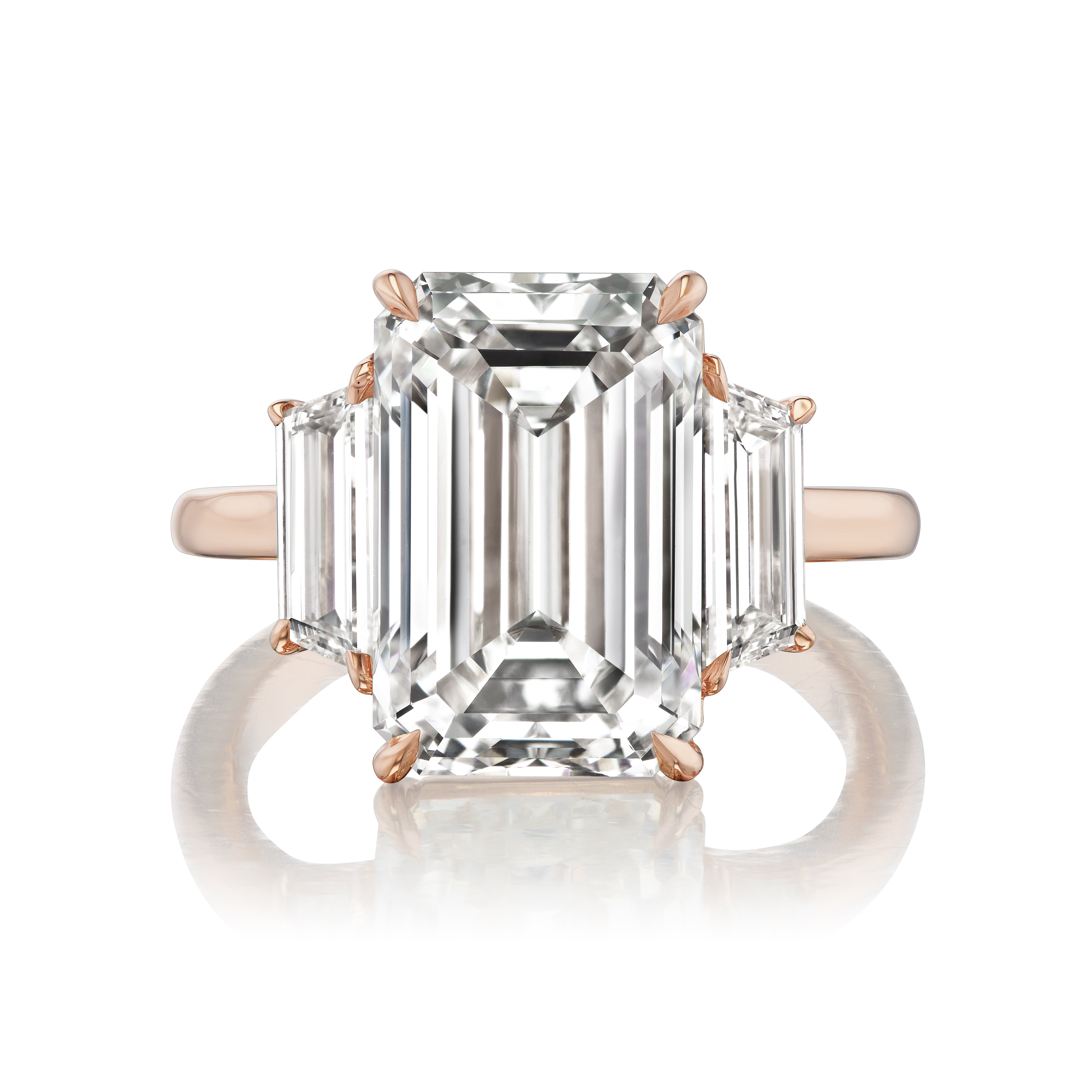 The Emerald Cut Diamond Engagement Ring with Trapezoid Side Stones showcases a large emerald-cut center diamond and two trapezoid side stones, set in rose gold and presented on a white background.