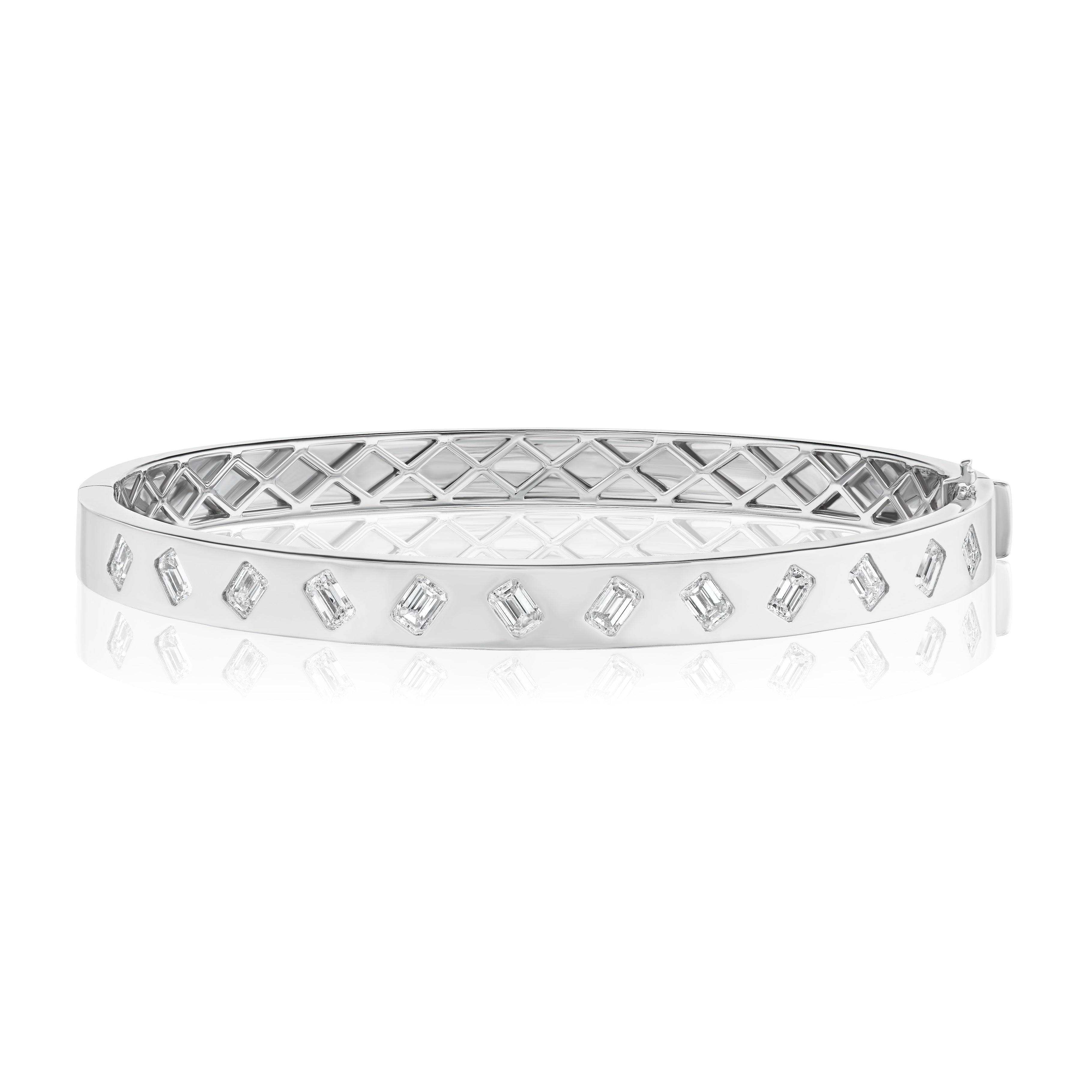 The Diagonally Burnish Set Alternating Emerald Cut Diamond Bangle in White Gold features VS clarity emerald cut diamonds set along the outer surface and a geometric inner pattern.