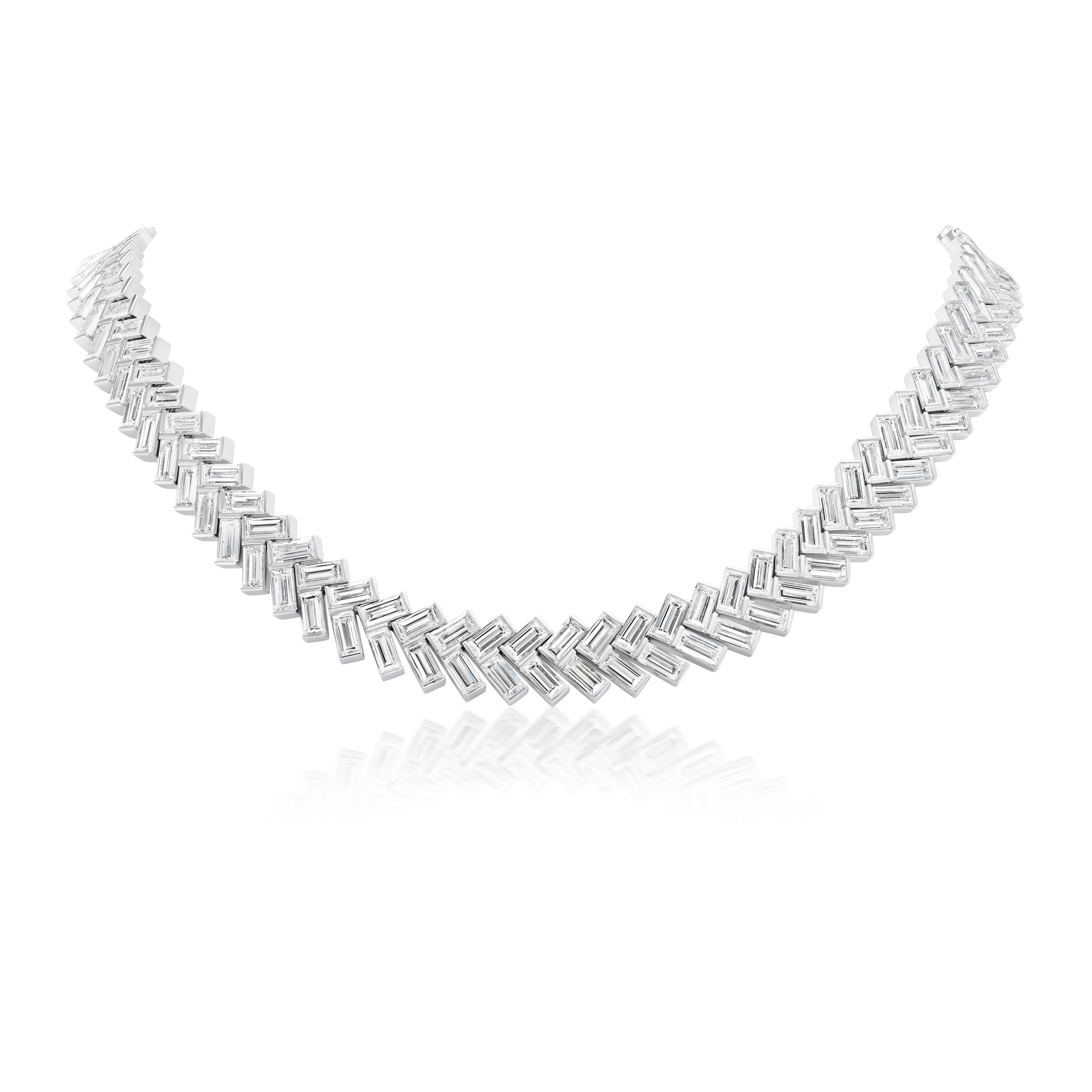 The Bezel Set Chevron Diamond Tennis Necklace in White Gold features a repeating chevron pattern of rectangular links, crafted in 18K white gold and shown on a reflective white background.