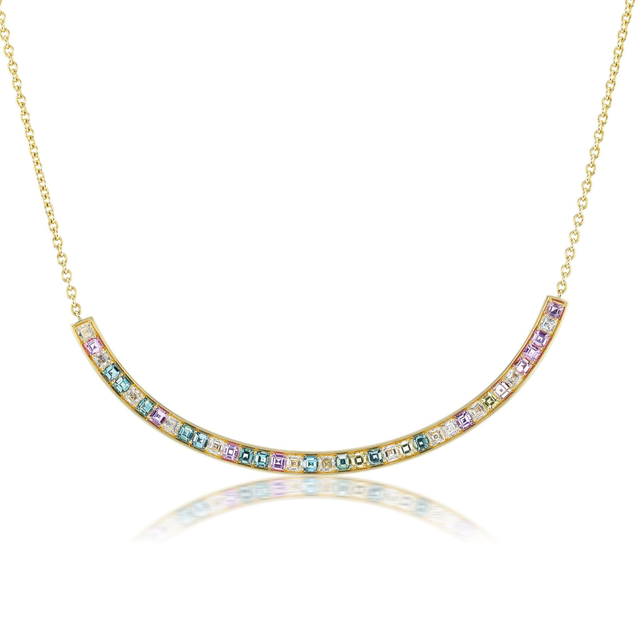 The Ombré Smile Bar Necklace in yellow gold features a curved bar with Asscher cut diamonds and multicolor sapphires, beautifully reflected on a white surface.