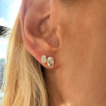 Close-up of a person’s ear wearing Duo Studs in White Gold with Oval Diamonds. Blonde hair appears nearby and sunlight highlights the sparkly, made-to-order 18K earrings.