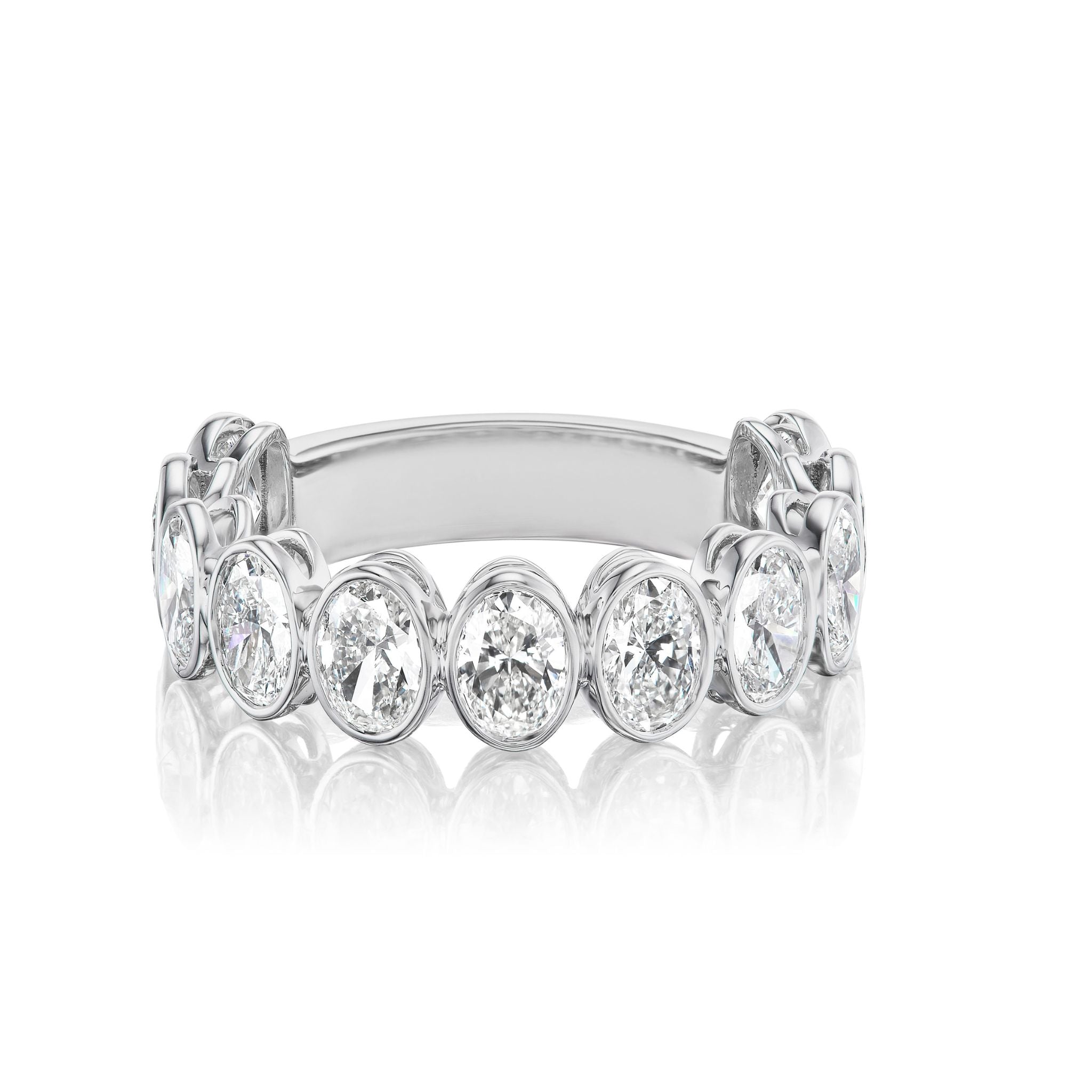 The Oval Bezel Set Diamond Half Eternity Band features bezel-set oval diamonds spaced halfway around the white gold band, displayed against a white background.