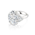 The Oval Diamond Engagement Ring with Heart Shape Side Stones is displayed on a white background, featuring a platinum band with a large oval diamond center and two heart-shaped side diamonds.