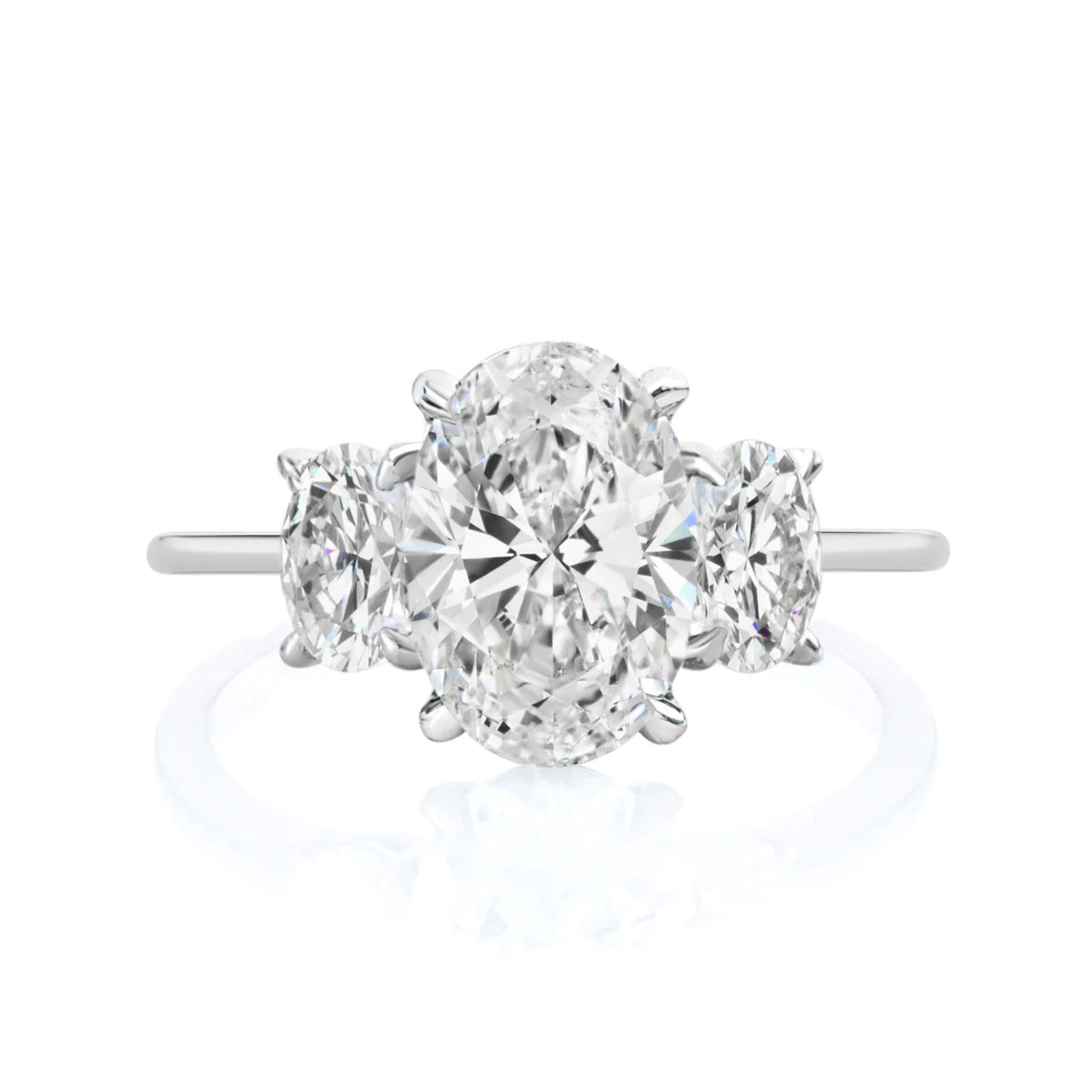 The Oval Diamond Engagement Ring with Oval Side Stones features a large center oval diamond and two smaller ovals on each side, set on a slim band—ideal for bridal or engagement rings and adding elegant sparkle to any occasion.