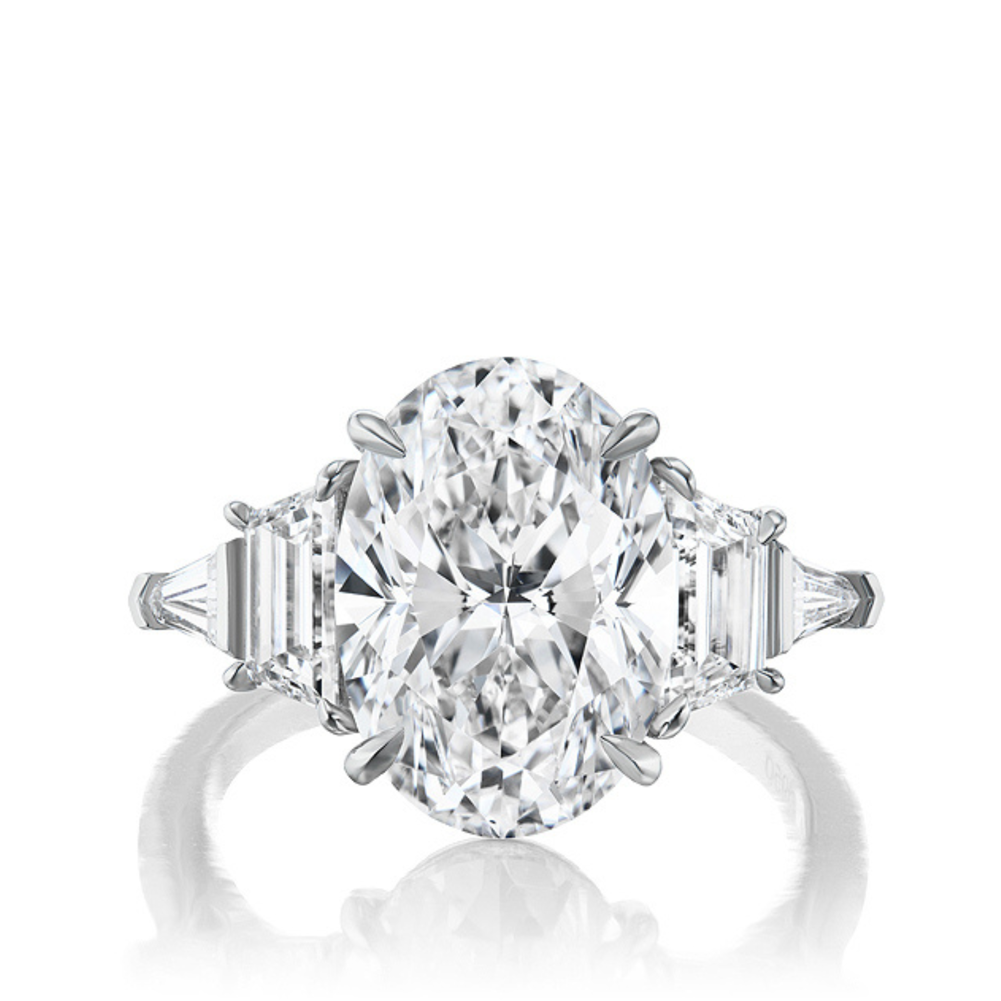 The Oval Diamond Engagement Ring with Trapezoid and Tapered Baguette Side Stones features an oval center diamond on a polished platinum band, ideal for celebrations and shown against a white background.