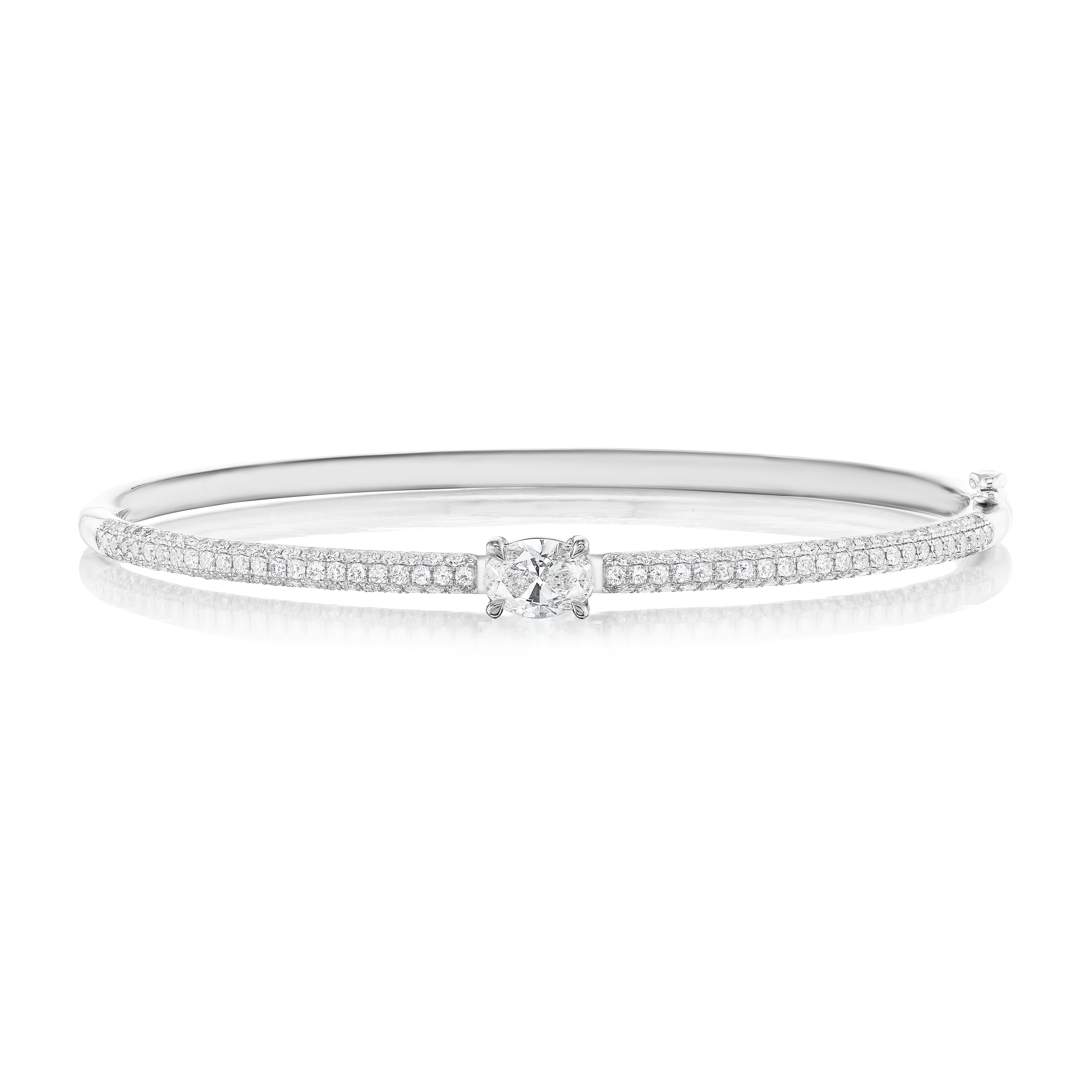 The East-West Set Oval Shape Diamond Pavé Bangle features two rows of small pavé diamonds along the band and a larger central diamond, shown against a white background.