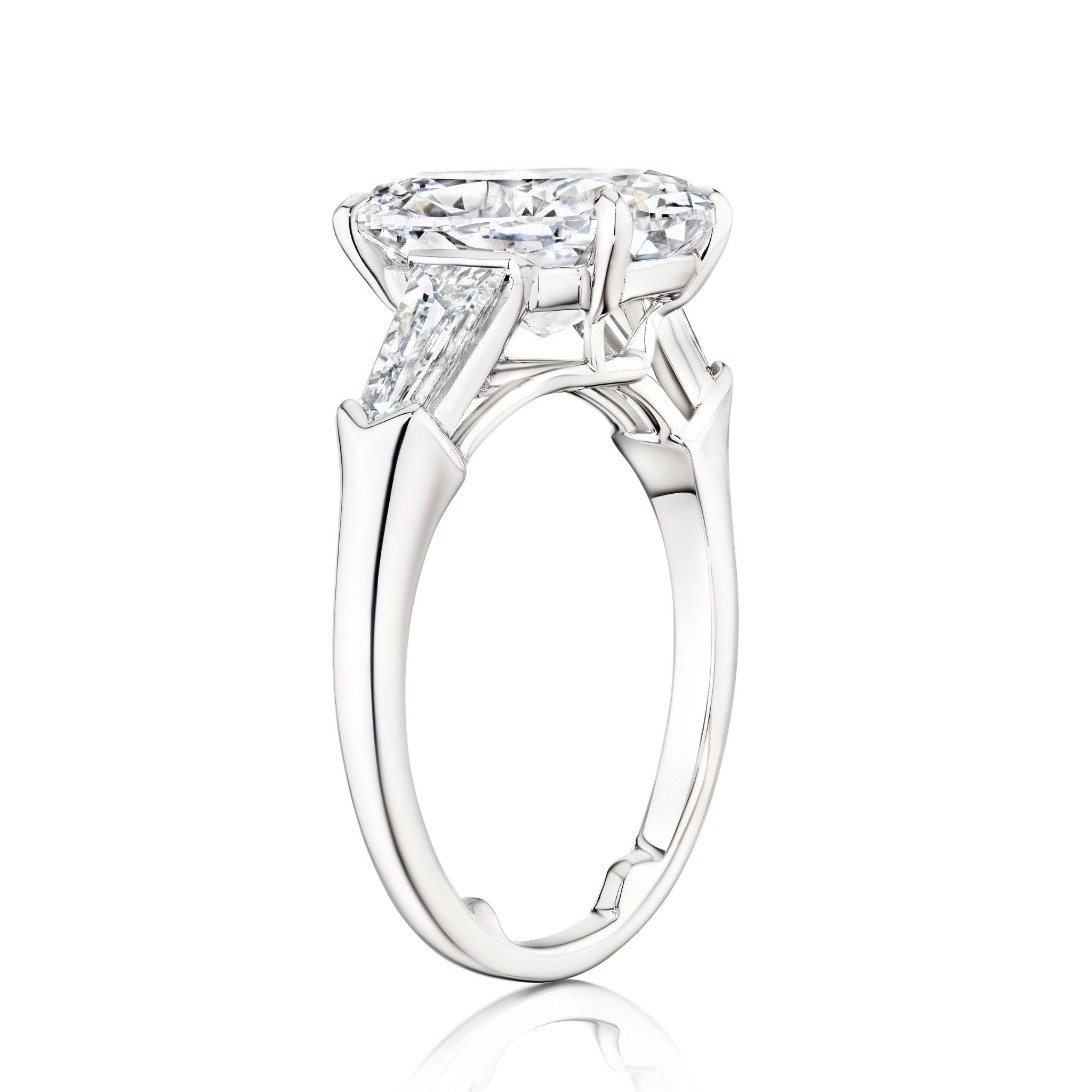 The Oval Shape Diamond Engagement Ring with Bullet Side Stones, crafted in platinum and photographed on a white background, features a striking oval center diamond flanked by two tapered baguette side stones.