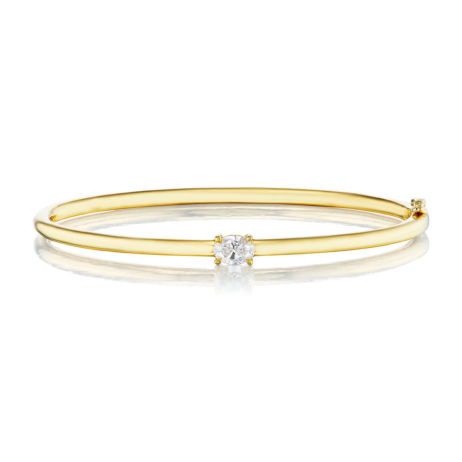 The East-West Oval Solitaire Diamond Bangle features a thin 18K yellow gold band with a single oval diamond in a minimalist prong setting at the center, shown on a white background.