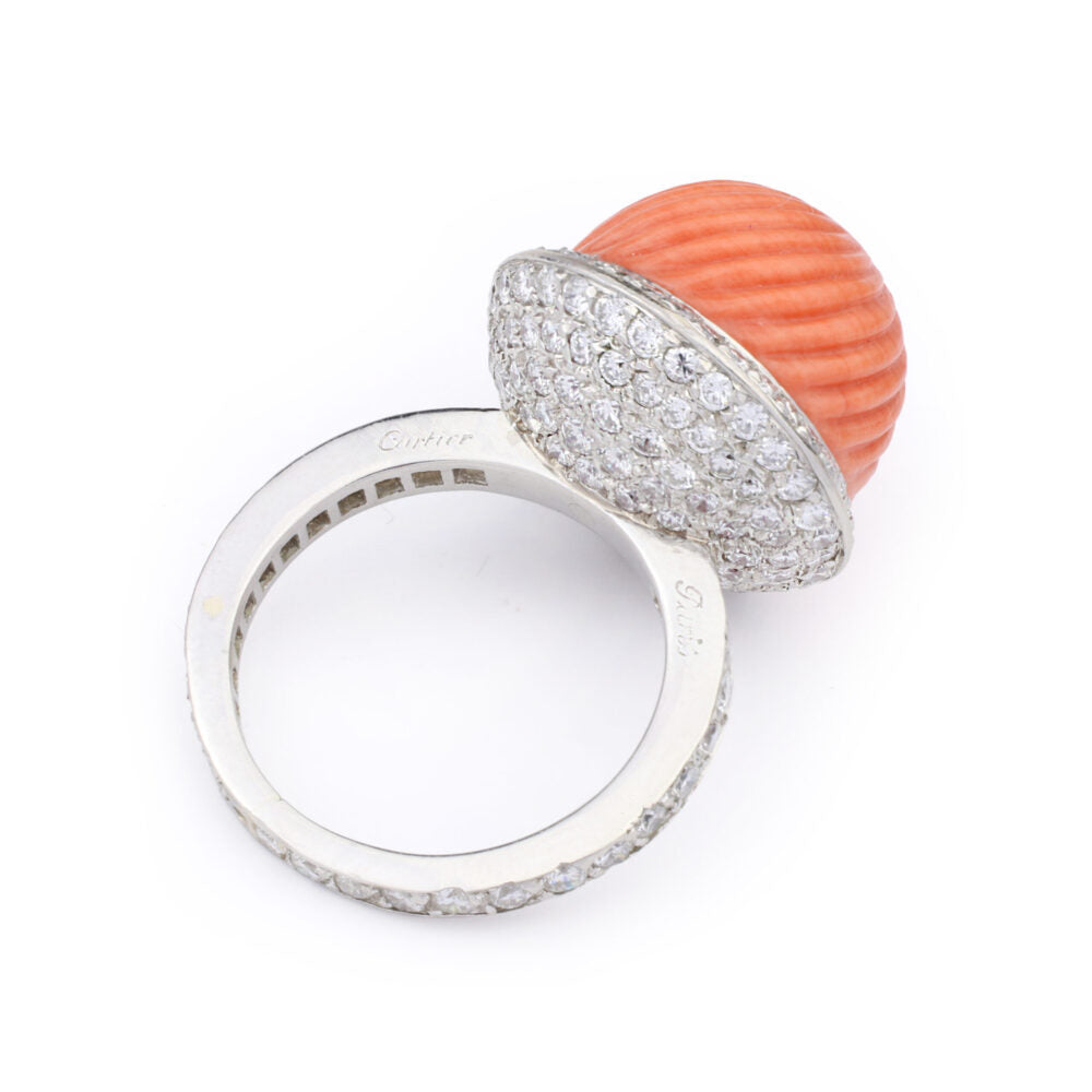 The Cartier Carved Coral and Diamond Ring features a large, textured coral dome set in silver atop a band encrusted with pavé diamonds.