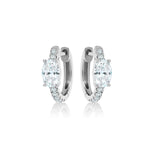 The Pavé Huggies with Oval Shape Diamond are silver hoop earrings featuring a large oval diamond at the center and smaller round stones set along the pavé trim on each front.