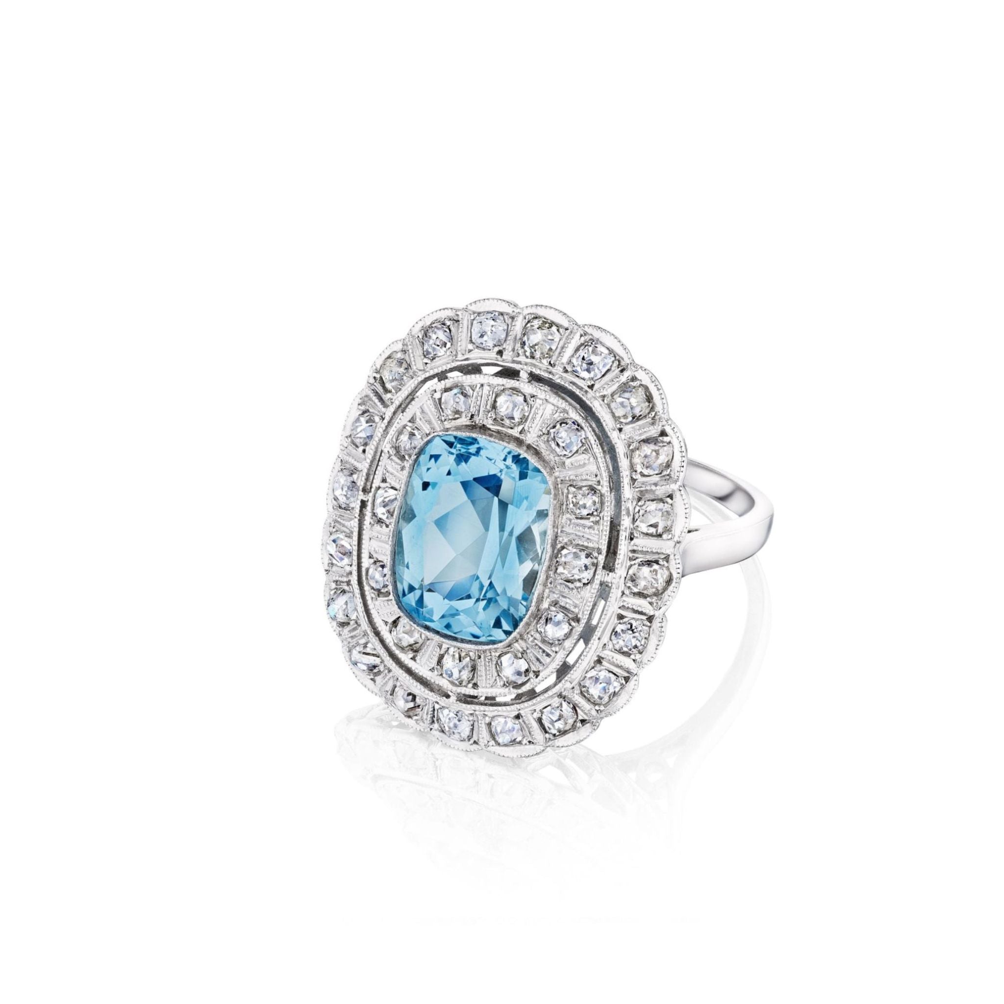 The Aquamarine and Diamond Ring is a platinum piece from the 1910s, showcasing a prominent cushion-cut aquamarine at its center, encircled by two rows of petite rose-cut diamonds, all presented against a white background.