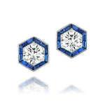 Introducing the Hexagonal Trapezoid Sapphire Stud Ear Jackets—elegant silver hexagonal stud earrings featuring a central round white gemstone, encircled by vibrant blue baguette-cut stones. These earrings can be paired with bespoke ear jackets for a personalized touch. Shown on a white background with subtle reflections beneath.
