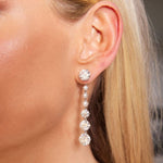 Close-up of a woman's ear adorned with the Graduated Drop Ear Jackets in White Gold, featuring a linear design set with luminous pearls and round brilliant diamonds. The sophisticated ear jacket style displays a stud at the top and three larger diamonds cascading below, adding exquisite sparkle and elegance.