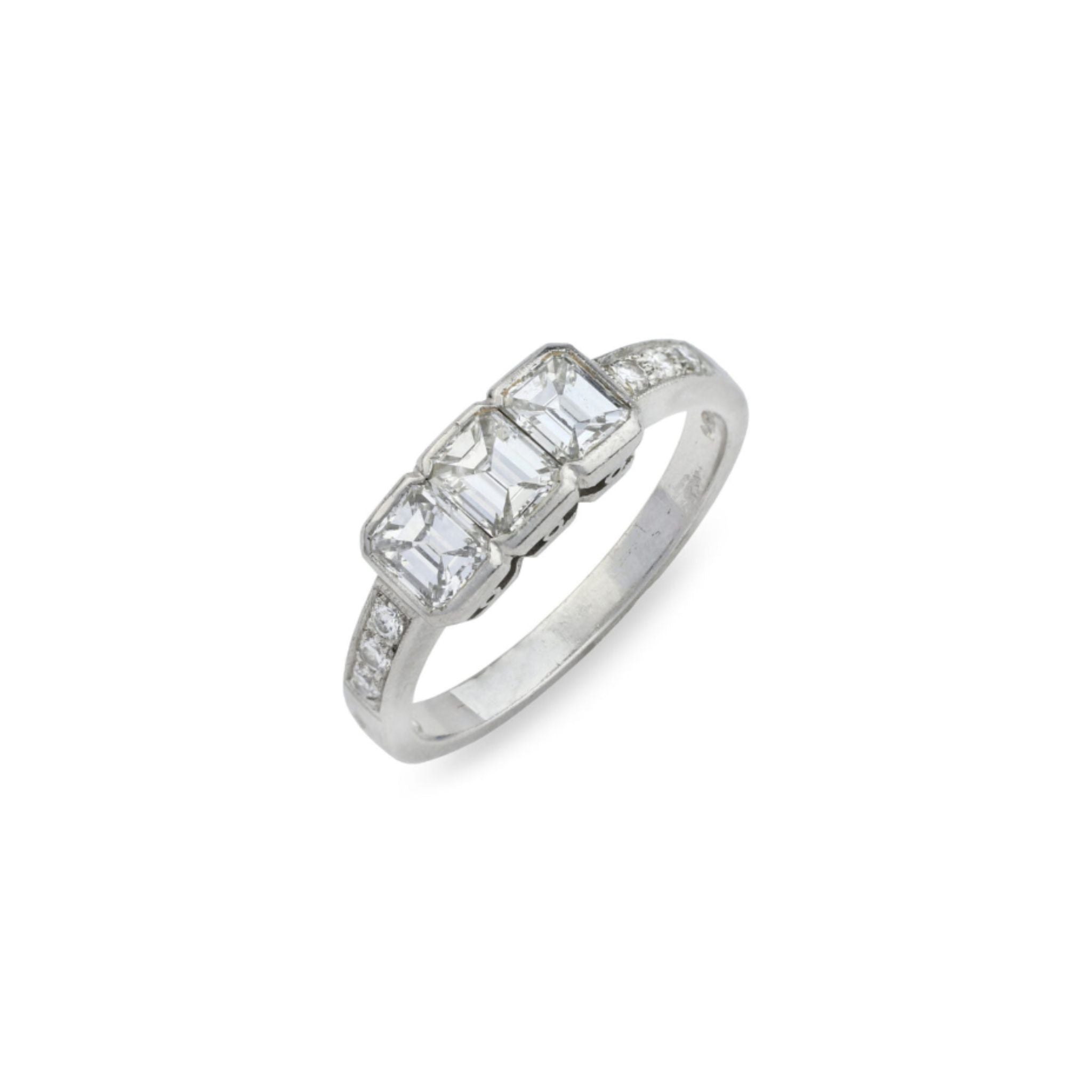 Introducing the 1950s Diamond Ring: a platinum piece showcasing three rectangular-shaped diamonds at its center, accented by smaller stones gracefully set along the band. This vintage-inspired ring is captured against a white background.