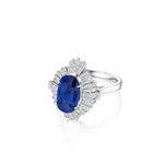 The Sapphire and Diamond Ring showcases a breathtaking large oval Ceylon sapphire as its centerpiece, encircled by a dazzling halo of baguette and round-cut white diamonds set on an elegant polished platinum band; it comes with a GIA report for your peace of mind.