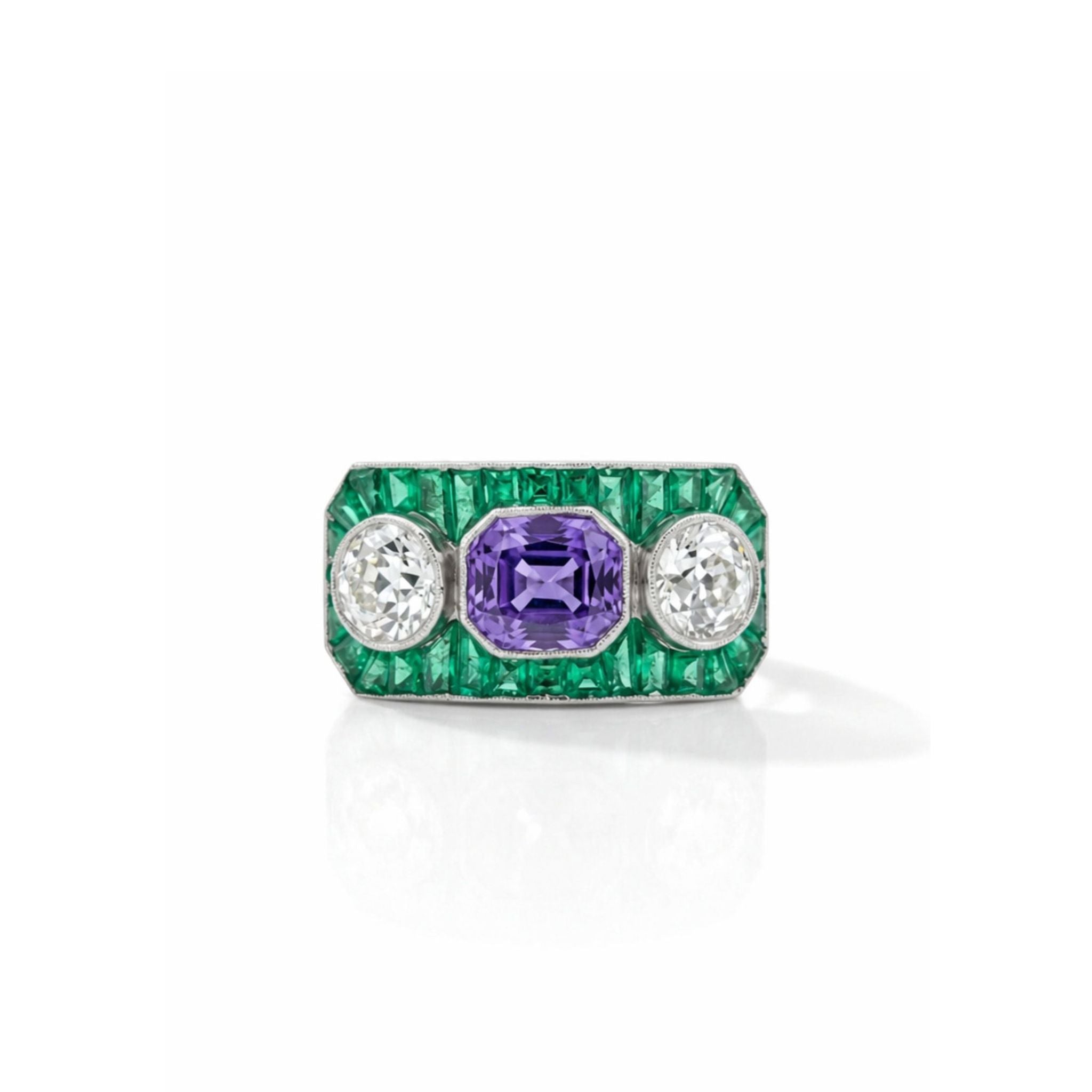 Product Name: Sapphire, Emerald and Diamond Ring A vintage platinum ring featuring a rectangular emerald-cut sapphire as the central purple gemstone, accented by two old European-cut diamonds and bordered by a row of petite emerald gemstones.