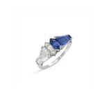 A Sapphire and Diamond Ring with a geometric design, showcasing a large blue sapphire gemstone and clear, angular-cut diamonds arranged in an art deco style on a white background, evoking the vintage elegance of the 1940s.