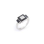 The Vintage Onyx and Diamond Ring showcases a central rectangular clear diamond, framed by onyx with black geometric accents, all set on a platinum band against a plain white background.