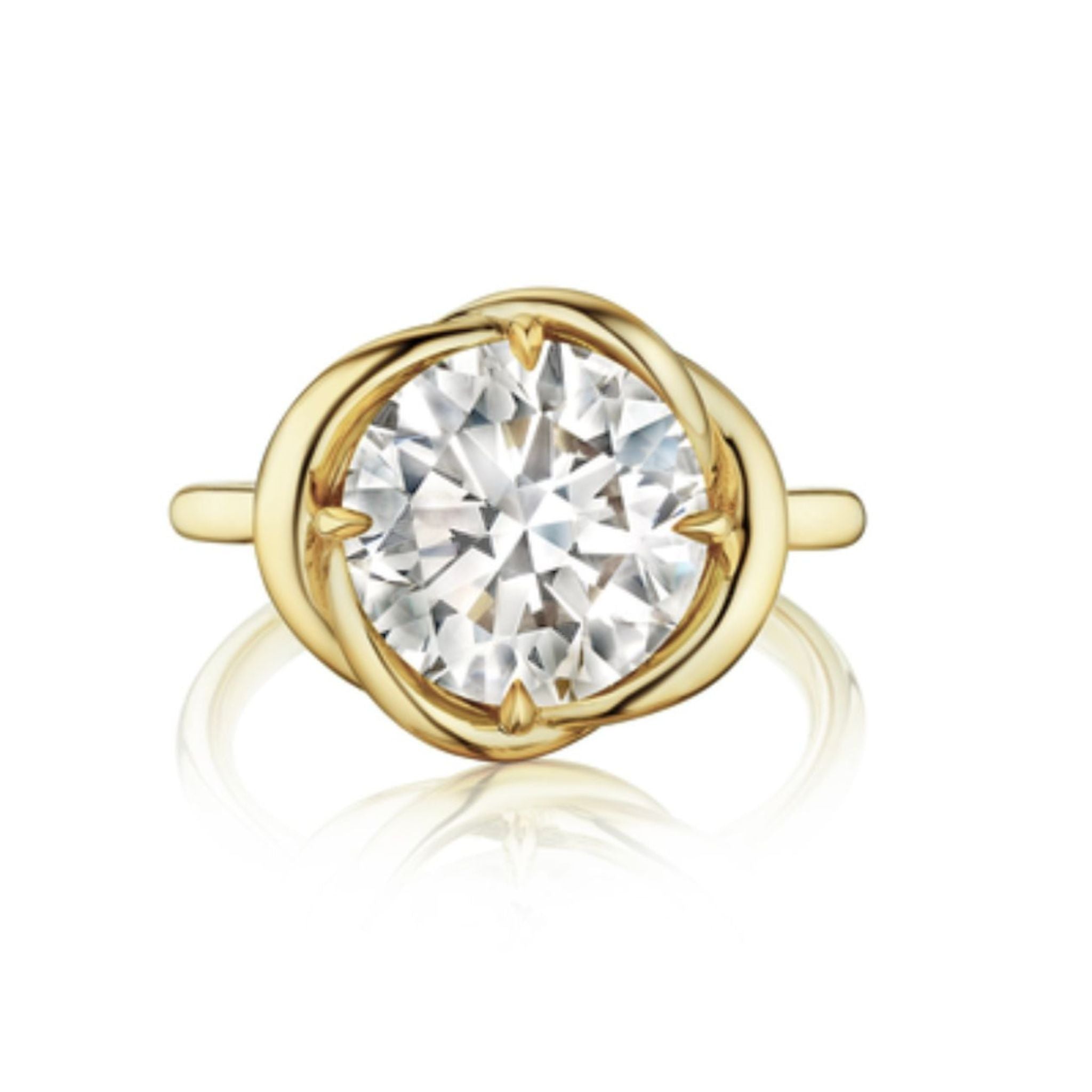 The Round Brilliant Diamond Engagement Ring features a large round-cut diamond set in an intertwining yellow gold band with four prongs securing the center stone.