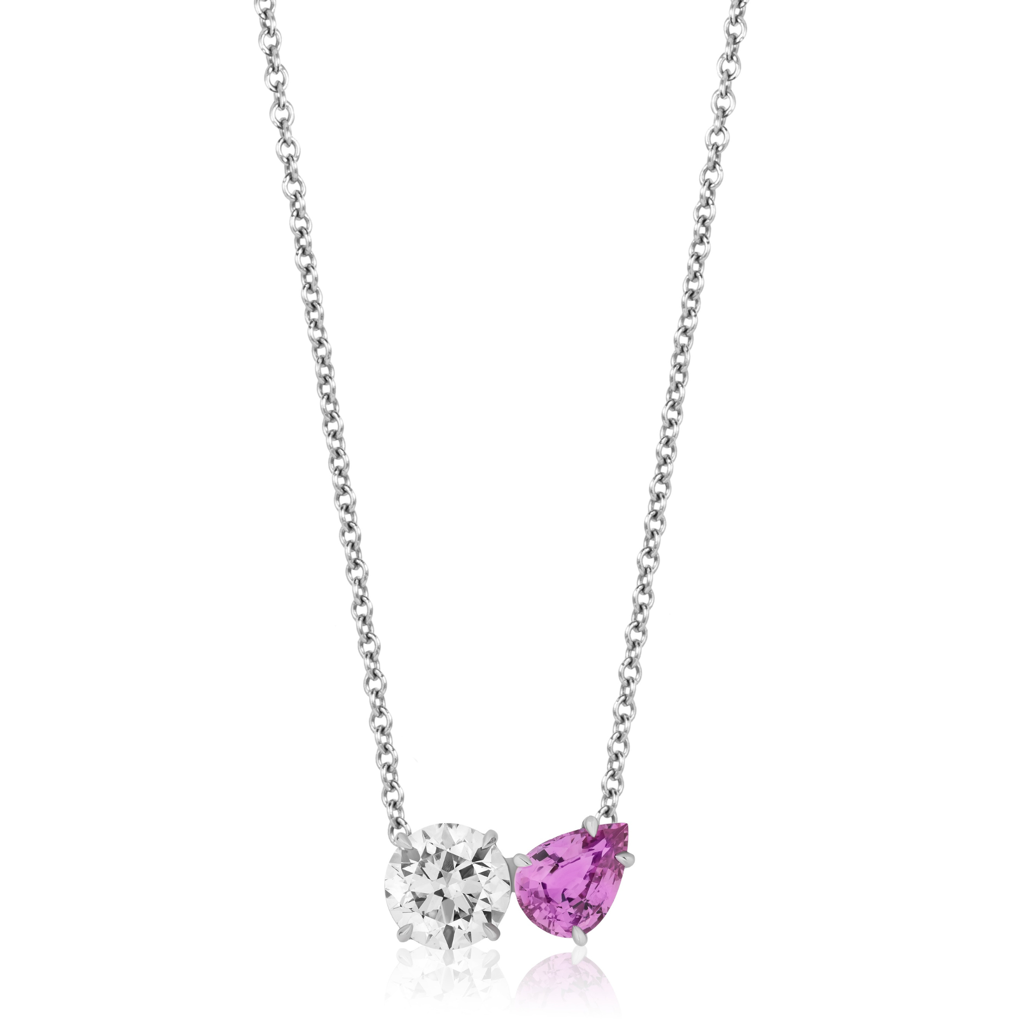 The Round Diamond and Pear Shape Pink Sapphire Toi Et Moi Pendant in White Gold showcases side-by-side pendants on a silver chain: a round diamond and a pear shape pink sapphire, both set in 18k white gold.