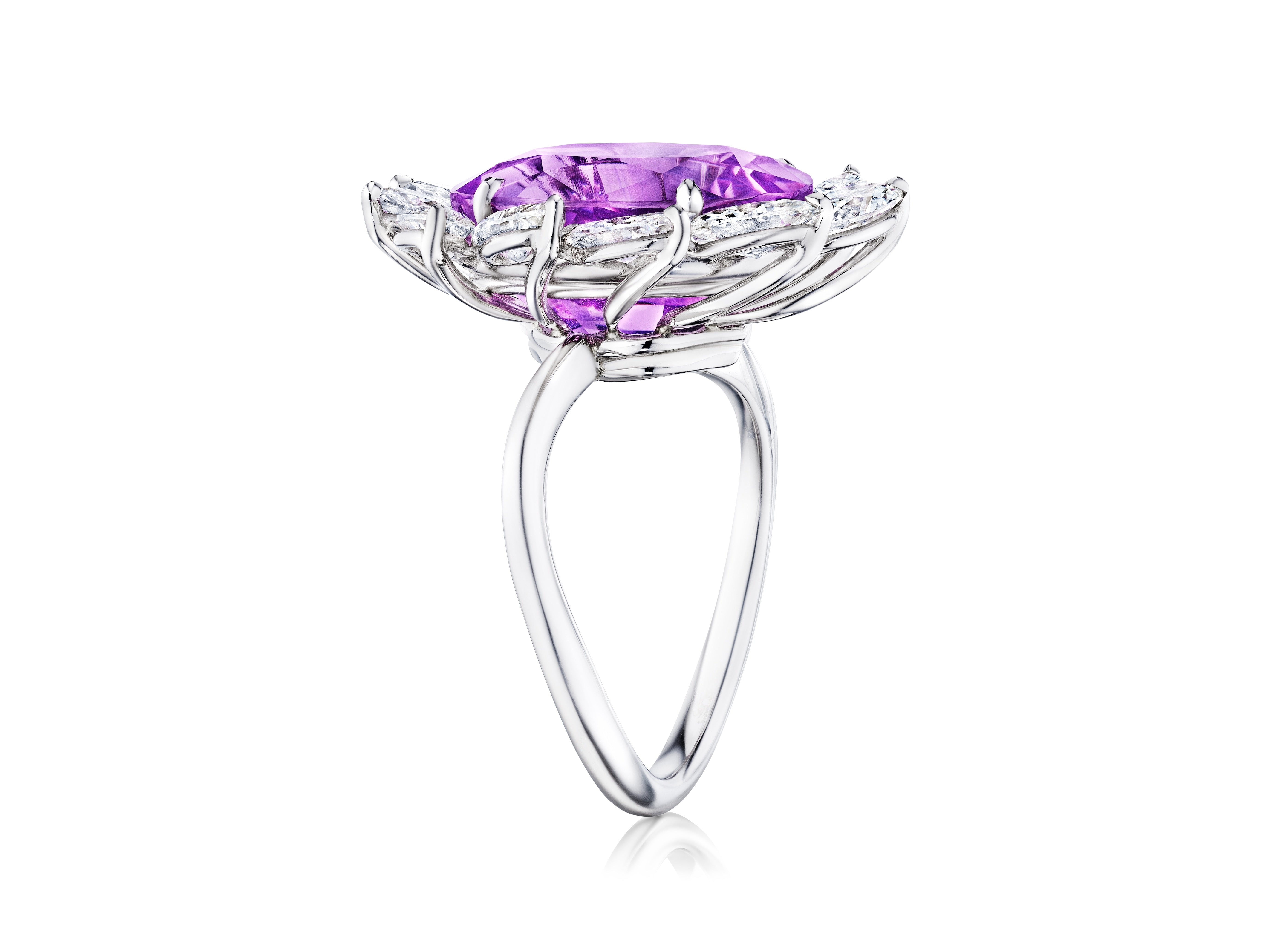The Sunburst Cocktail Ring features an oval sapphire at the center, surrounded by a marquise diamond halo and set in silver, displayed on a white background.