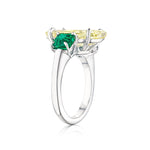 A side view of the Step Cut Oval Yellow Diamond Engagement Ring with Square Emerald Side Stones in white gold, featuring a large oval yellow diamond centerpiece and smaller square emerald accents on an 18K white gold band against a plain white background.